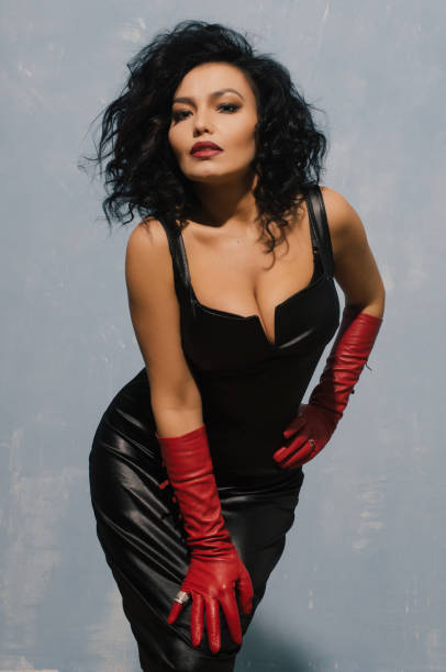 luksusowa azjatka pozuje w czarnej skórzanej sukience i czerwonych rękawiczkach. dominująca fetysz lady. - corset gothic style fetish wear women zdjęcia i obrazy z banku zdjęć