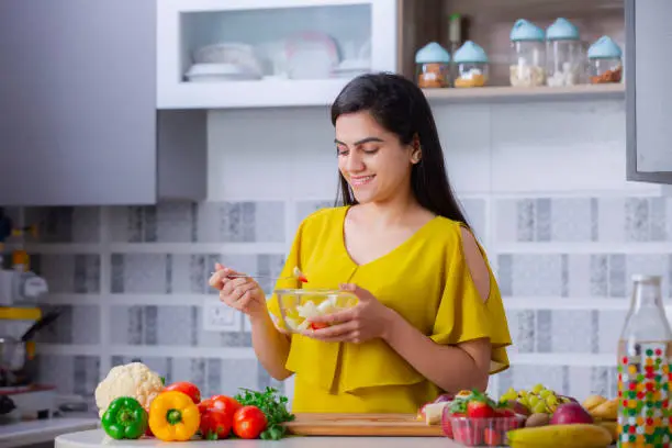 Photo of Young woman cutting fruit in the kitchen stock phot