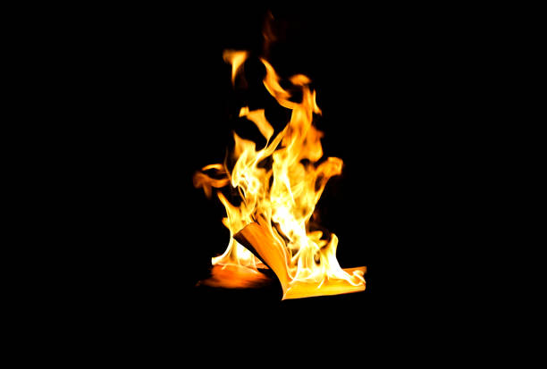 Man is holding burning book on fire at night. People don't like reading. Intellectual problems.
