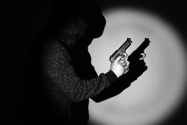 istock Man with gun. Shadow in the spotlight. Criminal concept. 1255348072