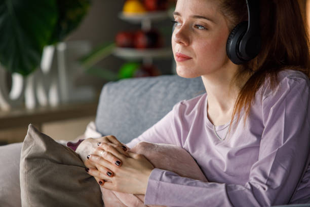 giovane donna che si rilassa e ascolta un audiolibri tramite cuffie - the thinker audio foto e immagini stock