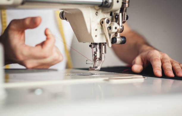 istock Close-up man hands sewing fabric on sewing machine 1255356590