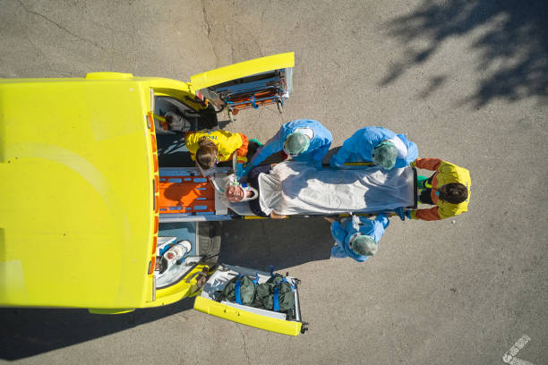 High angle view of senior Caucasian man on stretcher being removed from ambulance by EMS and hospital medical teams.