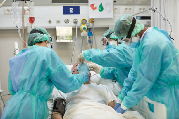 istock Nurses in Protective Wear Caring for Man in Hospital Bed 1255356853
