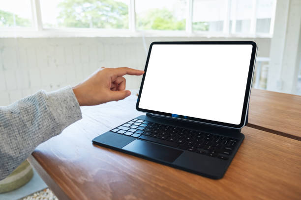 istock a woman using and pointing finger at tablet pc with blank desktop white screen as a computer pc on wooden table 1255358474