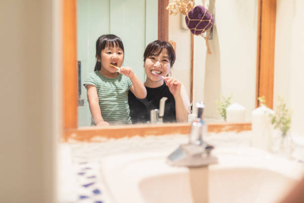 istock Mother and daughter brushing teeth in labotary at home 1255360410