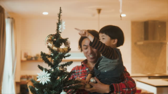 Japanese father is decorating christmas tree with his children