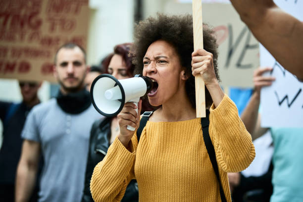 istock Black female activist shouting through megaphone on a protest. 1255361308