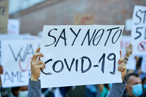Close-up of person holding banner with say NO to COVID-19 inscription on a protest during coronavirus epidemic.