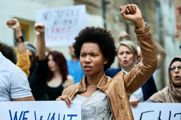 african american woman with raised fist participating in a protest for human rights. - anti racism imagens e fotografias de stock