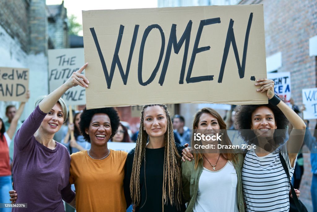 Happy united women protesting for their rights on street demonstrations. Multi-ethnic group of happy females on a demonstrations for women's rights. Only Women Stock Photo