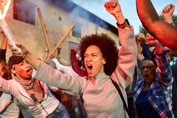 Furious crowd of people participating on public demonstrations. Furious black woman and group of activists shouting while protesting for human rights on the streets. police brutality photos stock pictures, royalty-free photos & images