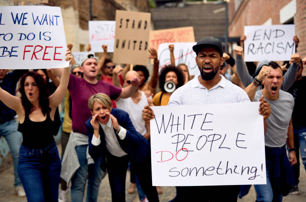 We can change the world if we are united! Multi-ethnic crowd of people protesting on anti-racism demonstrations. Focus is on black man holding banner with White People Do Something inscription. police brutality photos stock pictures, royalty-free photos & images