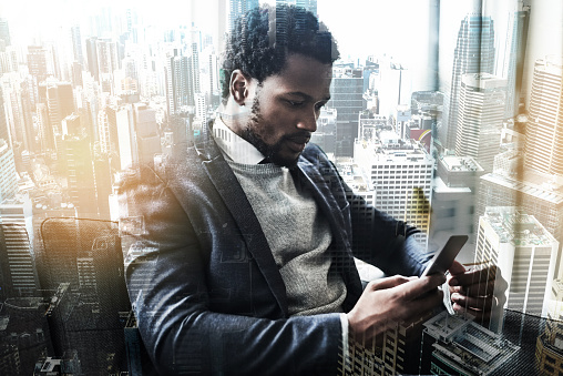 Shot of a young businessman using a smartphone superimposed on a city background