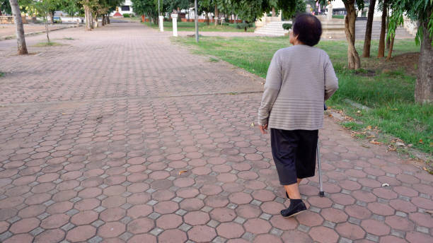 istock senior woman walking with walking stick in park 1255365106