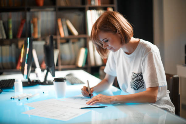 istock Young pretty designer is developing new project, workspace in creative company against the background of bookshelves 1255366290