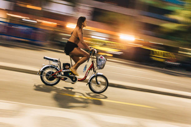 junge frau fährt nachts e-bike an der ipanema beach sea avenue - brazil bicycle rio de janeiro outdoors stock-fotos und bilder