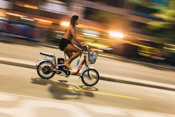 joven mujer montando e-bike en la avenida costera de ipanema beach por la noche - brazil bicycle rio de janeiro outdoors fotografías e imágenes de stock