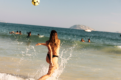 Young Brazilian woman playing Futebol at Ipanema Beach, Rio de Janeiro, Brazil.