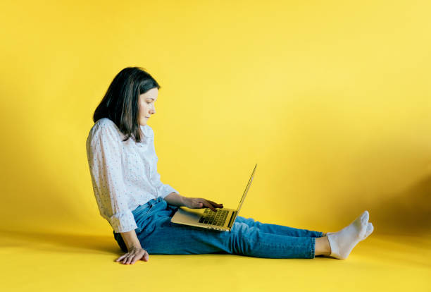 istock girl with a laptop on a yellow background 1255370678