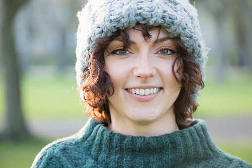 Backlit sunset portrait of young woman wearing a wooly hat and knitted sweater - autumn / winter outdoors.