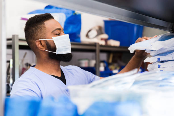 Confident nurse prepares for his shift A mid adult African American male nurse prepares for his shift in a hospital ward by retrieving personal protective equipment from a hospital supply room. medical supplies stock pictures, royalty-free photos & images