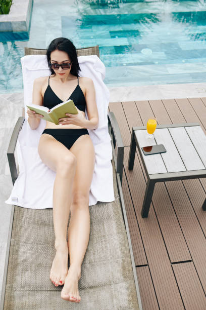 istock Woman reading by swimming pool 1255373427