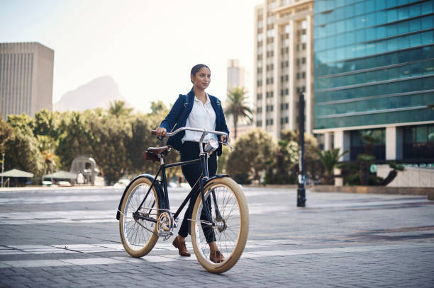 Let ambition lead the way Shot of a young businesswoman traveling with a bicycle through the city carbon footprint stock pictures, royalty-free photos & images