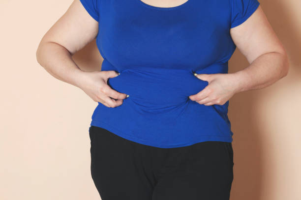istock woman hand belly fats 1255373920
