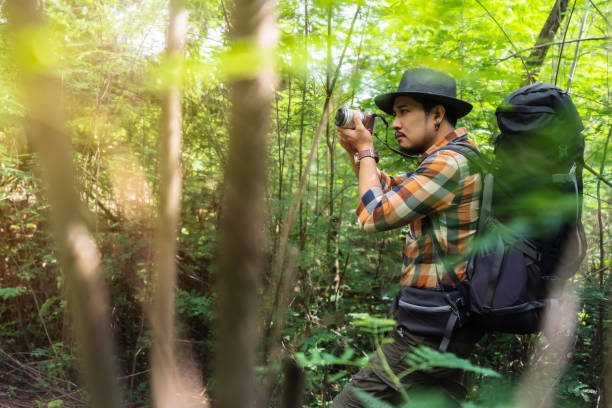 istock man traveler with backpack using camera to take a photo in the forest 1255374727