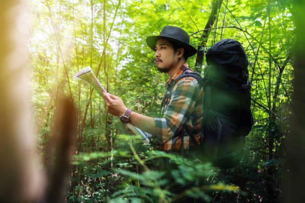 istock man traveler with backpack and map searching directions in the forest 1255374736