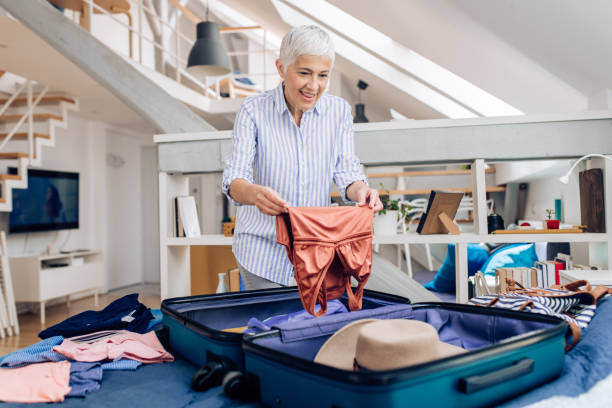 istock Happy mature woman packing for vacation 1255376356