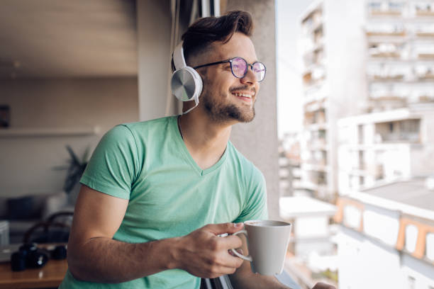 istock Young man enjoying the music and drinking coffee at home 1255376550