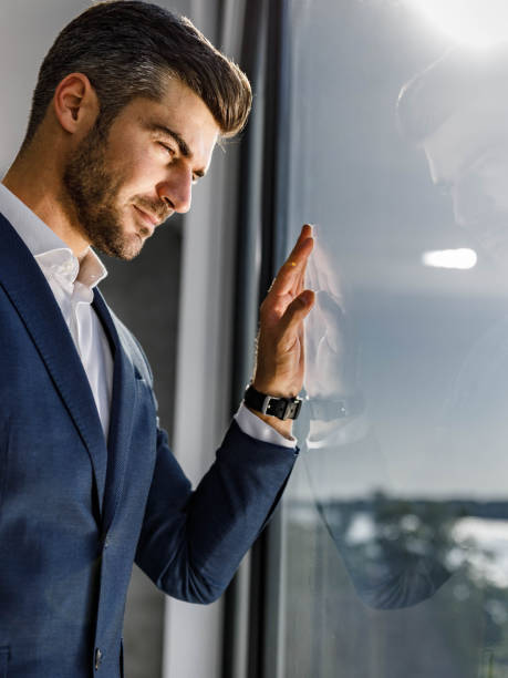 istock Pensive mid adult businessman looking through window. 1255376584