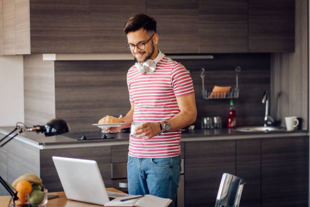 istock Young man bringing a breakfast to his home workplace 1255376685