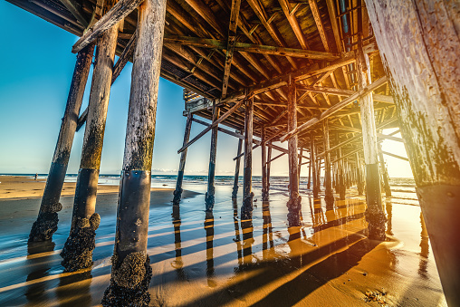 Newport Beach wooden pier seen from the ground at sunset. Orange County, Southern California