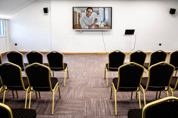 istock Happy businessman giving presentation over projection screen in empty conference hall. 1255380853