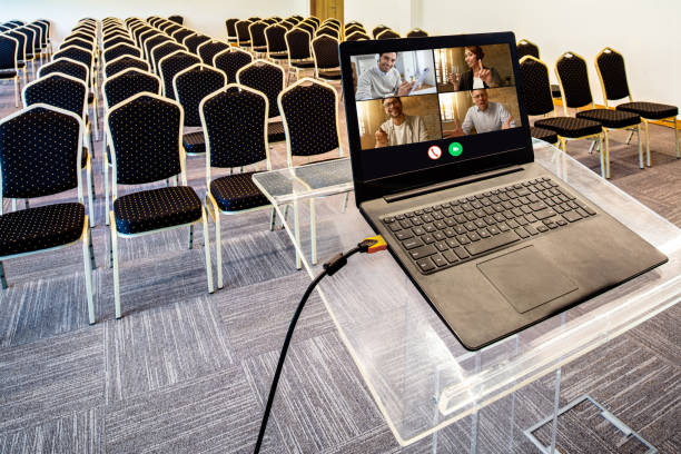 geschäftsleute, die eine telefonkonferenz über laptop im leeren kongresszentrum abhalten. - conference call convention center presentation podium stock-fotos und bilder