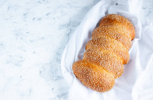 Freshly baked bread with sesame seeds on a white towel. Copy space for your text. Home baking concept.