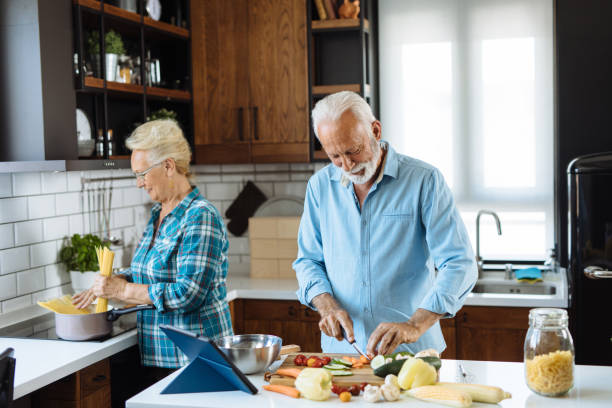 istock Cheerful senior couple preparing healthy meal using online recipe 1255386087