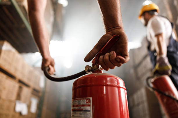 Close up of using fire extinguisher in a warehouse. Close up of unrecognizable worker using fire extinguisher in a storage room. extinguishing photos stock pictures, royalty-free photos & images
