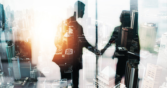 Superimposed shot of two businesspeople shaking hands in an office