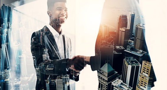 Superimposed shot of two businesspeople shaking hands in an office