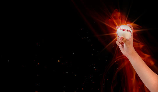 Hand grips baseball on flare, Pitcher Baseball Player Holding Baseball In Hand Ready to Throw the Ball fire.