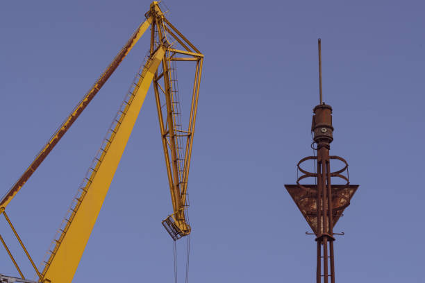 Crane and rusted warning siren at a shipyard, against a clear sky.  Belfast, Northern Ireland.