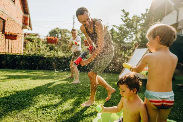 Photo of a happy family enjoying in a water battle in their yard