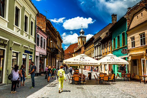 Brasov, Romania - 23 June, 2020: color image depicting the ancient cobbled streets of Brasov, a city in the Transylvania region of Romania. Romania has just opened up after the Covid-19 lockdown, and people are beginning to enjoy the terraces, bars, restaurants and shops of this charming city once again.