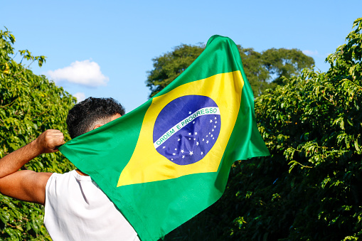 Holding the Brazilian flag in the wind.