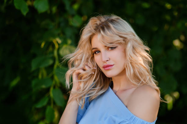 portrait of a young beautiful girl 21 years old in a blue summer dress with a white belt bag. the woman smiles. beautiful lips and eyes. long loose hair. - sensuality walking women beautiful imagens e fotografias de stock