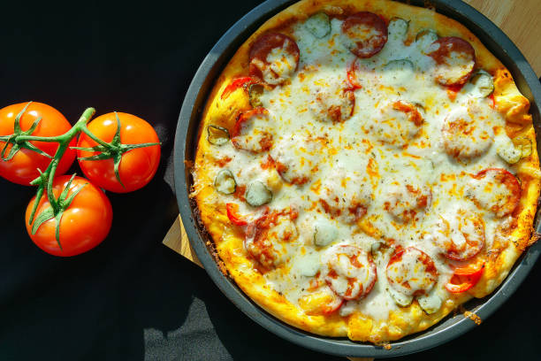 istock Fresh homemade pizza with pepperoni ingredients on a rustic background. Pizza with salami, garlic and fresh herbs. The view from the top. 1255401202
